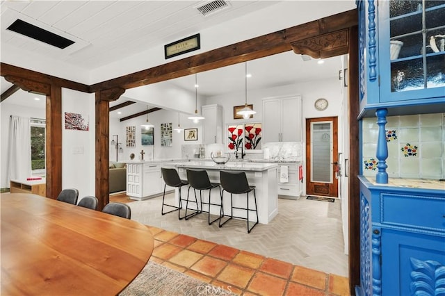 kitchen with white cabinetry, pendant lighting, a kitchen bar, and tasteful backsplash