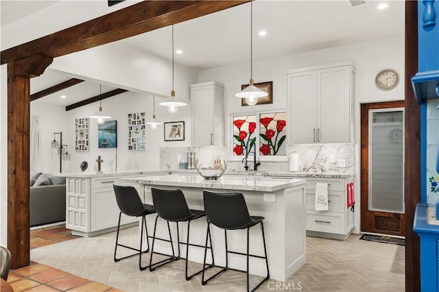 kitchen featuring white cabinets, backsplash, a kitchen bar, and a center island