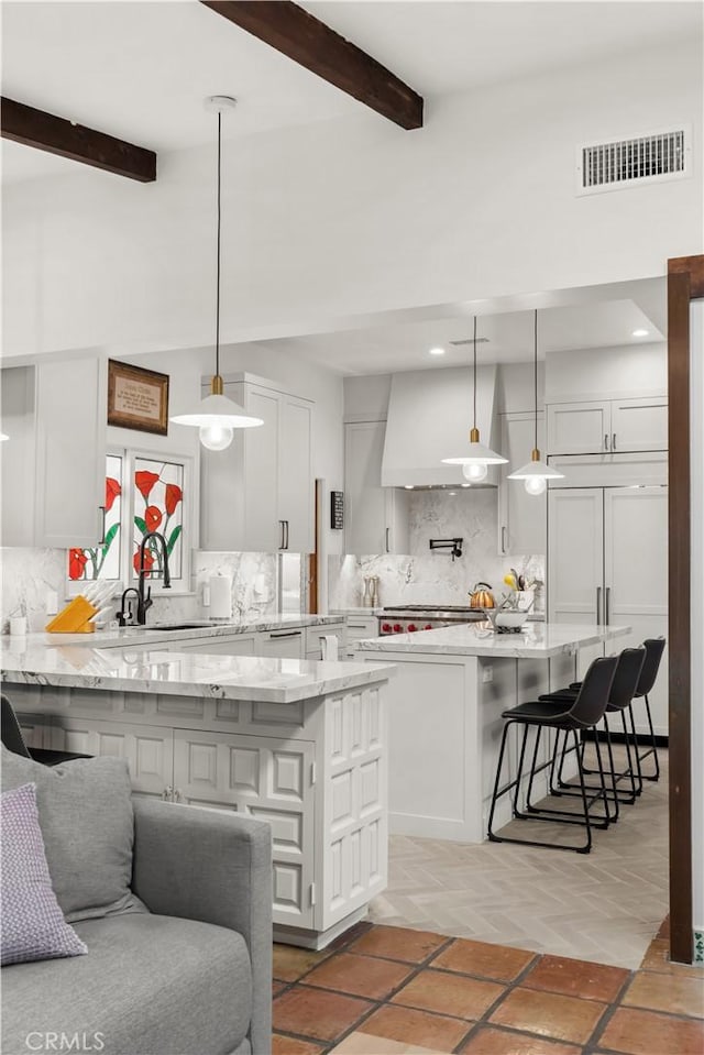 kitchen featuring hanging light fixtures, sink, backsplash, and beamed ceiling