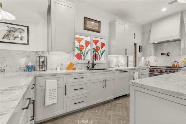 kitchen with backsplash, white cabinetry, stainless steel range, custom range hood, and light stone counters