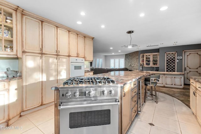 kitchen with stainless steel range, light tile patterned flooring, hanging light fixtures, and oven