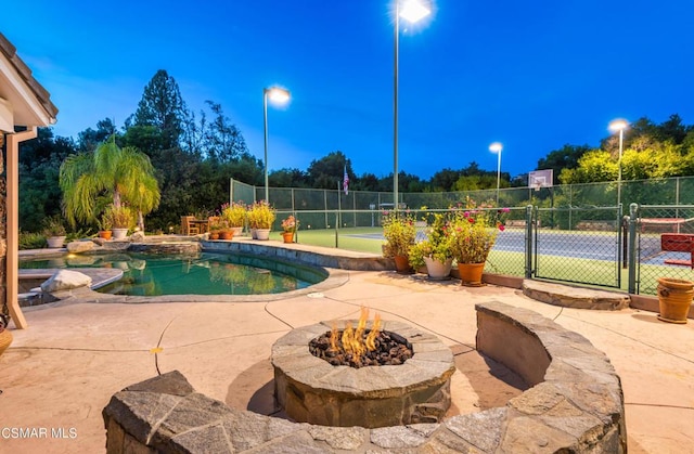 view of pool with tennis court and a fire pit