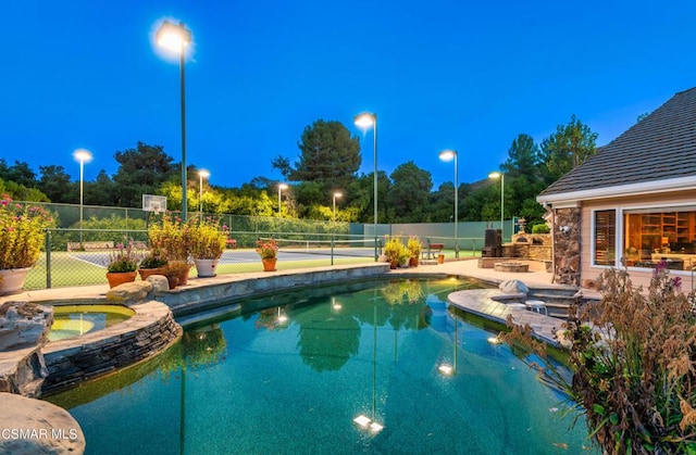 view of swimming pool with tennis court and an in ground hot tub