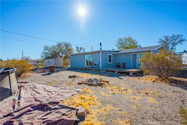 rear view of property featuring a deck and a storage unit