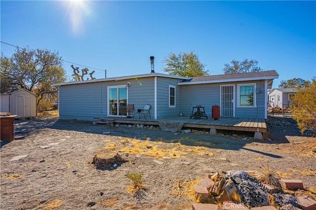 rear view of property featuring a shed and a wooden deck