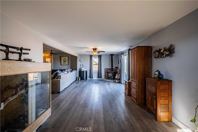 interior space with ceiling fan, a wood stove, and dark hardwood / wood-style floors