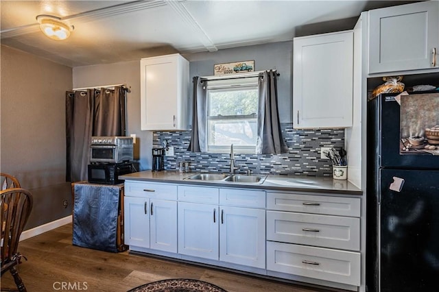 kitchen with black appliances, decorative backsplash, sink, white cabinetry, and dark wood-type flooring