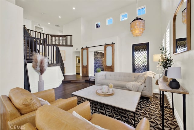 living room featuring a towering ceiling, dark hardwood / wood-style flooring, and a barn door