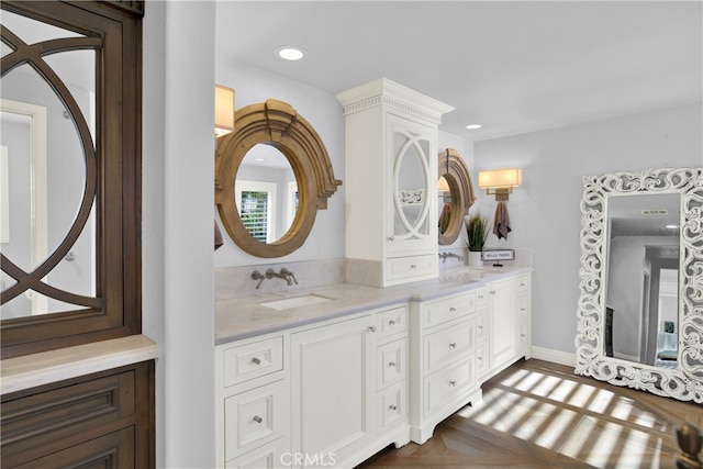 full bathroom featuring double vanity, baseboards, a sink, and recessed lighting