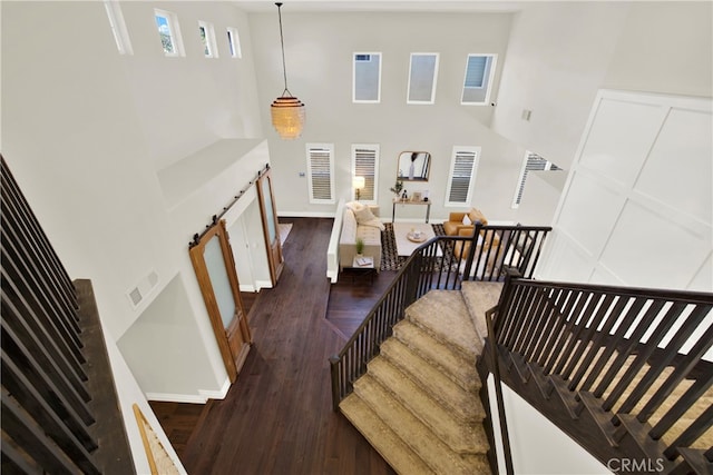 stairway with baseboards, a high ceiling, visible vents, and wood finished floors