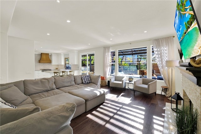 living room featuring a stone fireplace and dark wood-type flooring