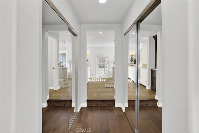 hallway featuring baseboards, dark wood finished floors, and recessed lighting