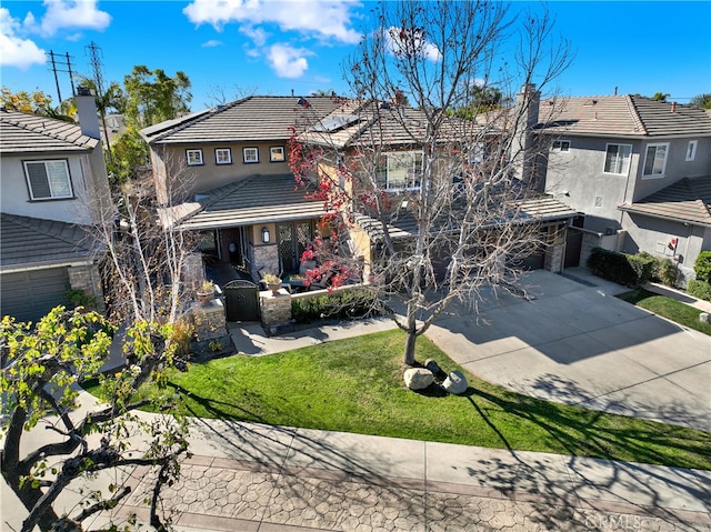 view of front of house featuring a garage, concrete driveway, a tile roof, a front yard, and stucco siding