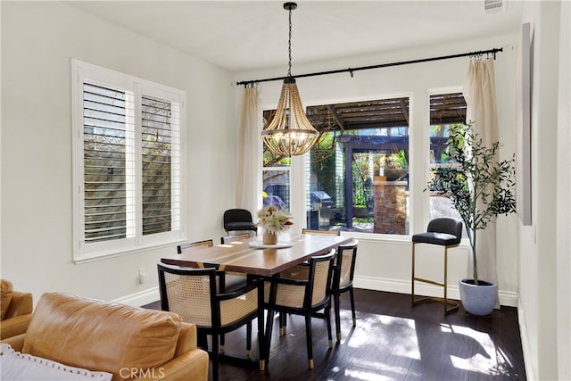 dining space with a chandelier, plenty of natural light, dark wood finished floors, and baseboards