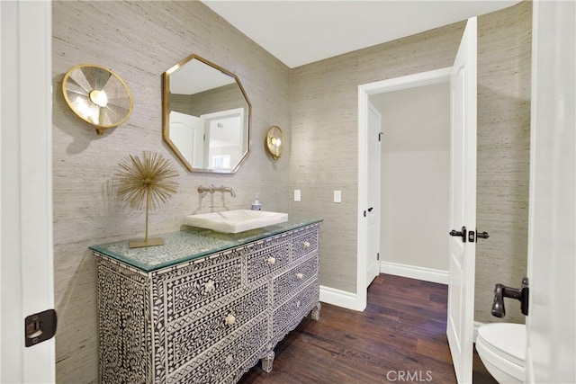 bathroom with toilet, baseboards, wood finished floors, and vanity