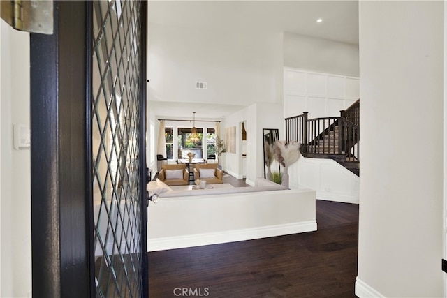 foyer with visible vents, stairway, a high ceiling, wood finished floors, and baseboards