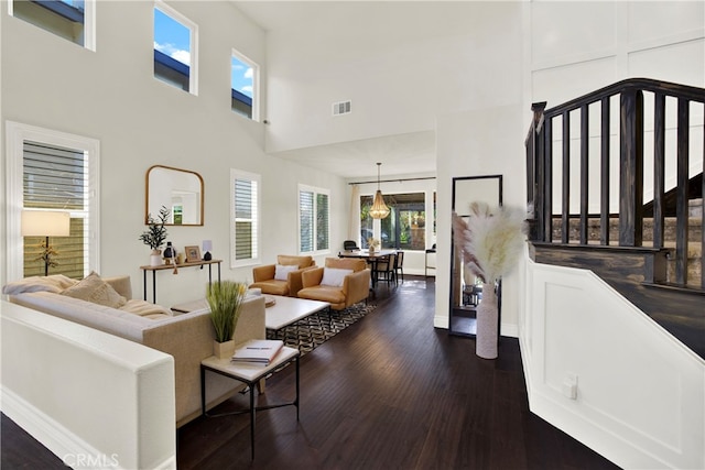 living room with dark wood-style flooring, visible vents, and a high ceiling