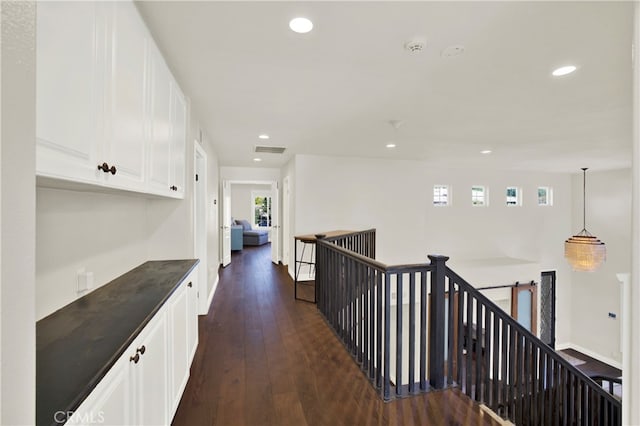 corridor featuring baseboards, dark wood-type flooring, an upstairs landing, and recessed lighting