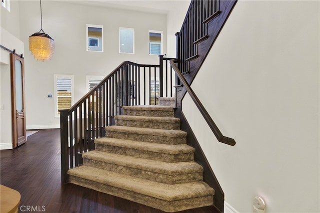 stairway with a high ceiling, a barn door, and wood-type flooring