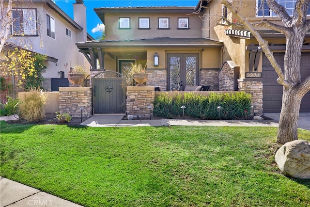 view of front facade with a garage, stone siding, a front lawn, and stucco siding