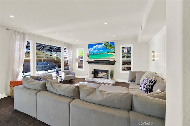 living area featuring dark wood-type flooring, a glass covered fireplace, baseboards, and recessed lighting