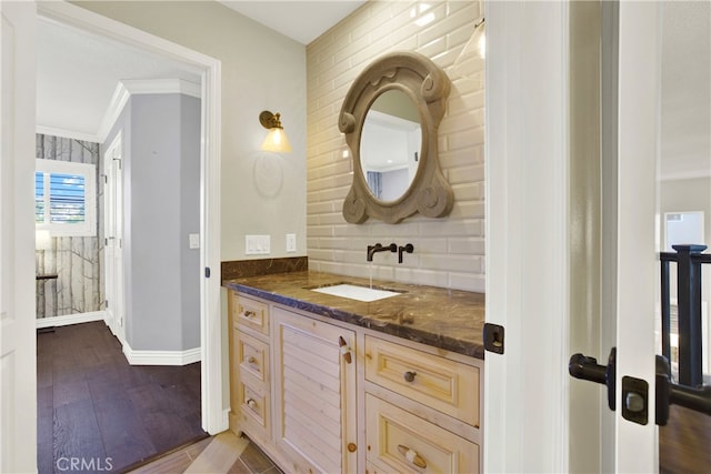 bathroom with wood-type flooring, backsplash, vanity, and ornamental molding