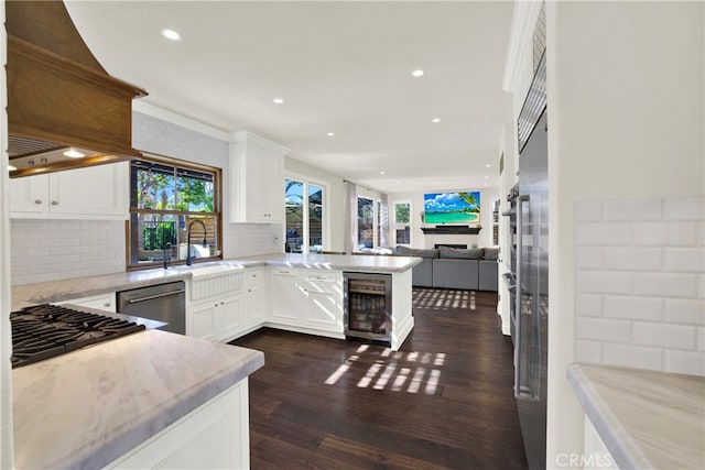 kitchen featuring beverage cooler, dishwasher, white cabinetry, backsplash, and kitchen peninsula