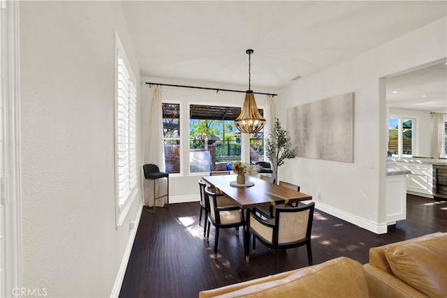 dining area featuring dark wood-type flooring, beverage cooler, an inviting chandelier, and a healthy amount of sunlight