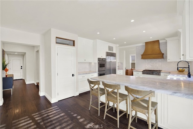 kitchen featuring white cabinetry, tasteful backsplash, sink, light stone counters, and custom range hood