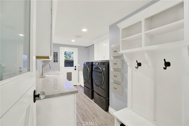 laundry area featuring cabinets, separate washer and dryer, sink, and light wood-type flooring