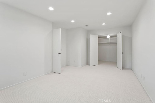 unfurnished bedroom with light carpet and a closet