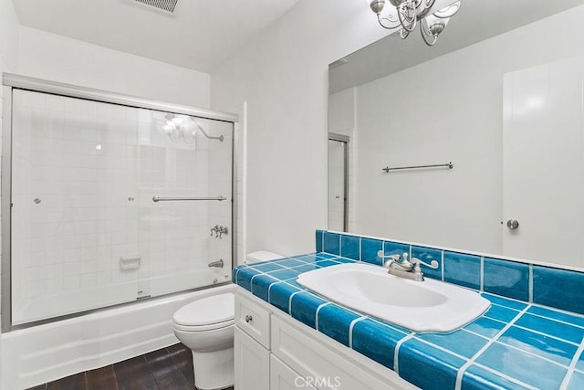 full bathroom featuring toilet, bath / shower combo with glass door, vanity, hardwood / wood-style flooring, and a chandelier