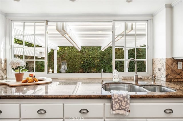 kitchen with tasteful backsplash, white cabinets, and sink