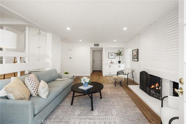 living room with a brick fireplace and light hardwood / wood-style flooring