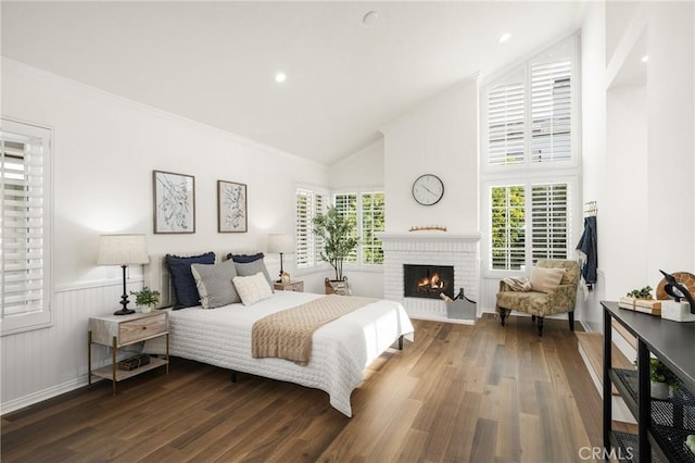 bedroom with a brick fireplace, dark hardwood / wood-style floors, and lofted ceiling