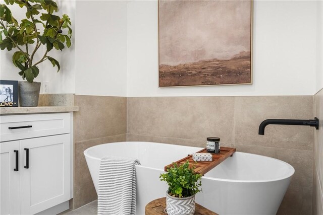 bathroom featuring a bath, tile walls, and vanity