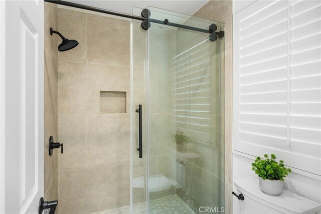 bathroom with toilet and a shower with shower door