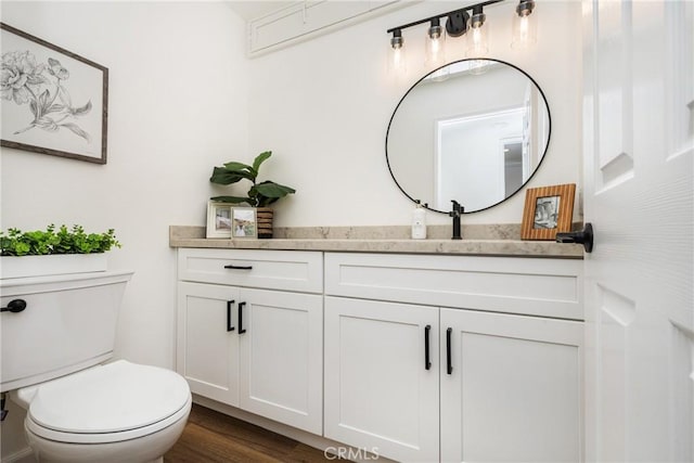 bathroom featuring wood-type flooring, toilet, and vanity