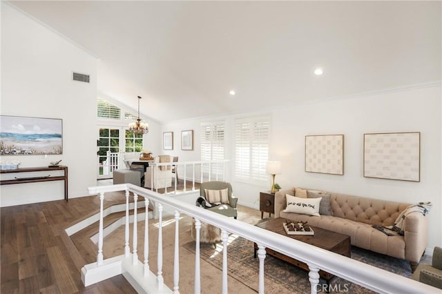 living room with high vaulted ceiling, dark wood-type flooring, ornamental molding, and an inviting chandelier