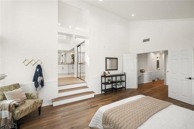 bedroom with high vaulted ceiling, dark wood-type flooring, connected bathroom, and ornamental molding