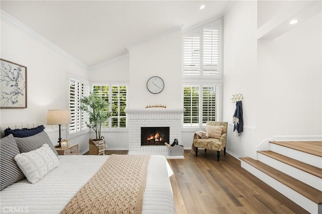 bedroom with a brick fireplace, ornamental molding, lofted ceiling, and hardwood / wood-style flooring