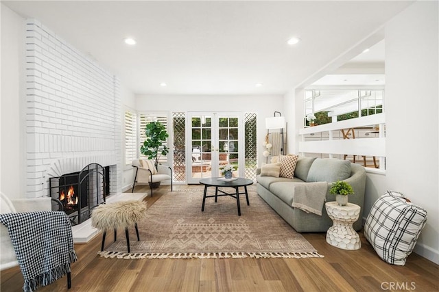 living room featuring french doors, a brick fireplace, and hardwood / wood-style flooring