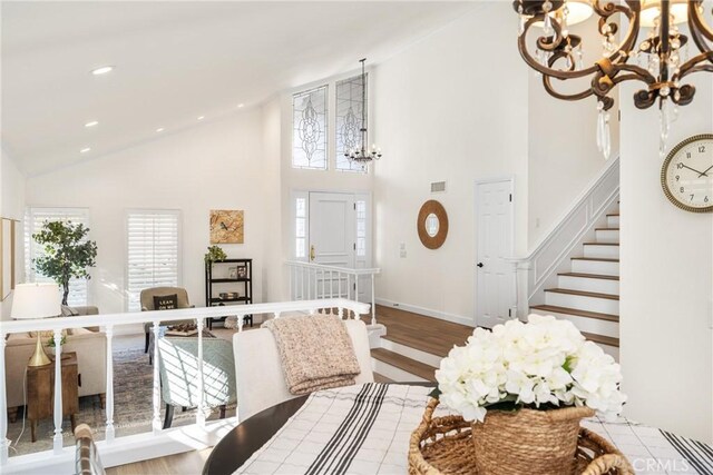 interior space featuring high vaulted ceiling, wood-type flooring, and an inviting chandelier