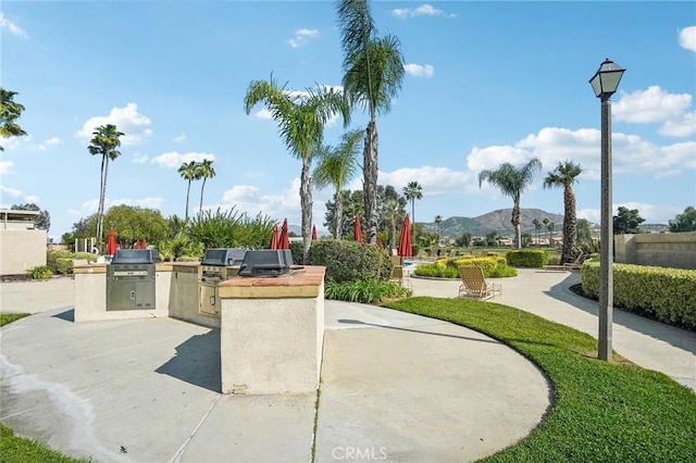 view of property's community with a patio, area for grilling, and a mountain view