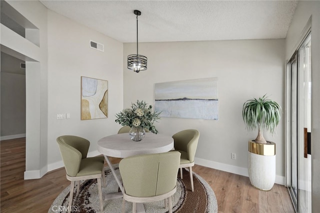 dining room featuring wood finished floors, visible vents, and baseboards