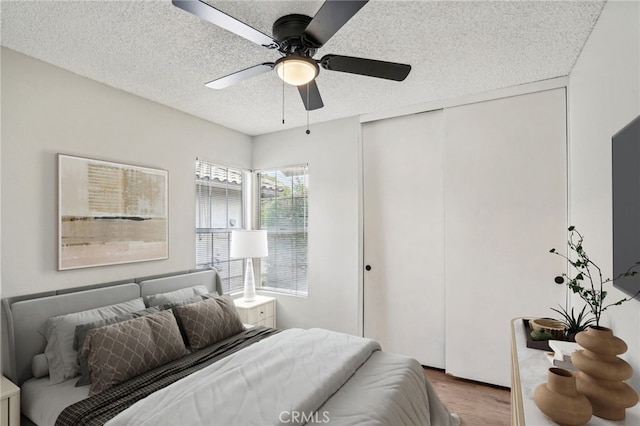 bedroom featuring a closet, ceiling fan, a textured ceiling, and wood finished floors