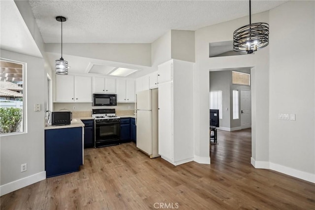 kitchen with range with gas stovetop, freestanding refrigerator, blue cabinets, light countertops, and black microwave