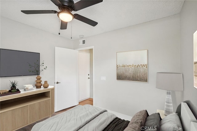 bedroom featuring ceiling fan, visible vents, and a textured ceiling