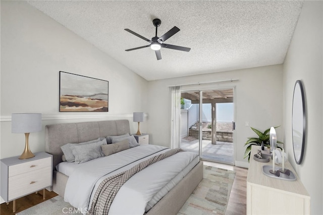 bedroom with lofted ceiling, a textured ceiling, a ceiling fan, access to exterior, and light wood-type flooring