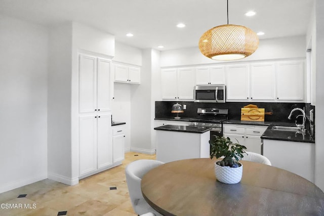 kitchen with appliances with stainless steel finishes, white cabinets, and decorative light fixtures